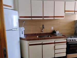 a kitchen with a sink and a white refrigerator at Apartamento 3 quarto Alto Bueno in Goiânia +3 photos
