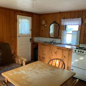 a kitchen with a table and a white stove at Gresham Shores - Lil' Sunfish - PET FRIENDLY in Arbor Vitae