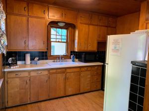 a kitchen with wooden cabinets and a white refrigerator at Gresham Shores - Big Dipper - PET FRIENDLY in Arbor Vitae