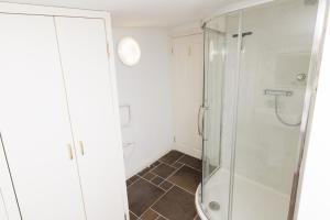 a bathroom with a glass shower and a tiled floor at Bains Closs, Shetland Islands in Lerwick