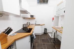 a kitchen with white cabinets and a brown tile floor at Bains Closs, Shetland Islands in Lerwick