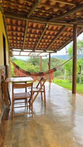 a hammock on a porch with a table and chairs at Pousada Velho Chico in Vargem Bonita