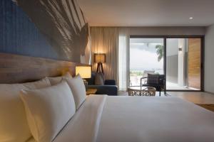 a bedroom with a large white bed and a living room at Mantra Samui Resort - Adults Only in Mae Nam