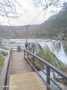 a wooden bridge over a river with a waterfall at Kamp Suad in Bihać