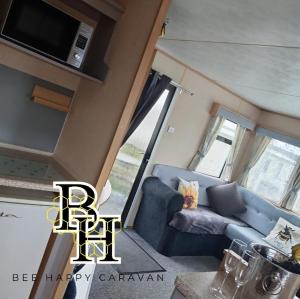 a living room with a blue couch and a tv at Bee Happy Caravan in Abergele