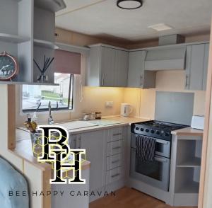 a kitchen with white cabinets and a stove top oven at Bee Happy Caravan in Abergele