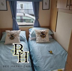 a couple of beds in a room with bees on them at Bee Happy Caravan in Abergele