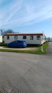a blue car parked in front of a trailer at Bee Happy Caravan in Abergele +10 photos