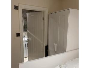 a bedroom with a mirror and a white cabinet at Quiet Double Room Ensuite Marble Bathroom South Croydon in Croydon +1 photo