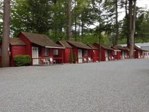 a row of red cabins in front of trees at Do-Rest Court in Lake George +16 photos