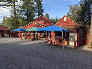 a barn with tables and blue umbrellas in front of it at Do-Rest Court in Lake George