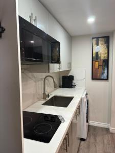 a white kitchen with a sink and a microwave at Joshie Stays in Hamilton +2 photos