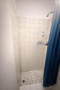 a shower with a blue shower curtain and a tile floor at Bonno Stay Suite in Gaborone +3 photos