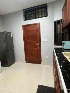 a kitchen with a wooden door and a refrigerator at Maison Sika in Zogbégan +4 photos
