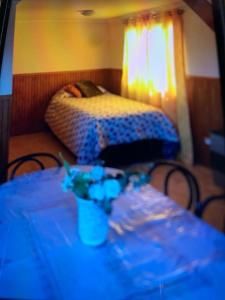 a room with a table with a bed and a table with flowers at Cabañas río seco in Punta Arenas