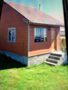 a small red house with a staircase in front of it at Cabañas río seco in Punta Arenas
