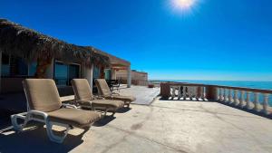 a row of chairs sitting on a patio next to the ocean at Recently Updated Beachfront Home Casa Neblina in Puerto Peñasco