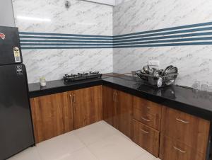 a kitchen with a black counter and a black refrigerator at Rahatani pimple Saudagar 2bhk in Chinchwad