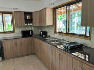 a kitchen with wooden cabinets and a sink and windows at Villa Maria Anse Corail in Takamaka