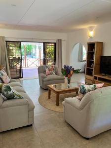a living room with three couches and a coffee table at Villa Maria Anse Corail in Takamaka