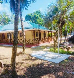 a yellow building with palm trees in front of it at Villa Maria Anse Corail in Takamaka