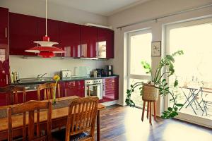 a kitchen with red cabinets and a table and chairs at Architektenwohnung in der Sternschanze in Hamburg