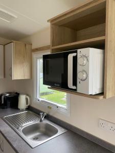 a kitchen with a microwave above a sink at Caravan Holiday Park in Newquay in Newquay