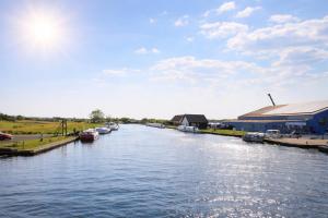 a river with boats docked next to a building at Thurnefield Holiday Cottages in Potter Heigham