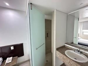 a bathroom with a sink and a shower with a mirror at Hotel Via 45 Centro in Medellín