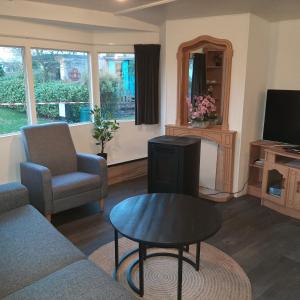 a living room with a couch and a table and a tv at Stacaravan in De Pol