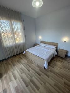a white bedroom with a large bed and wooden floors at Hotel RADOJA in Shkodër