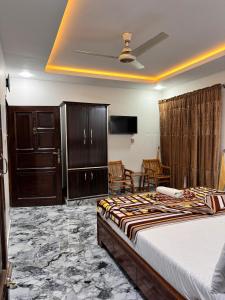 a bedroom with a bed and chairs in a room at The lodge Guest House in Muzaffarabad
