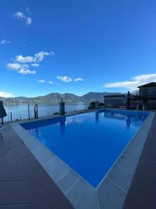 a large swimming pool with a blue sky and water at Residence Il Vigneto - Casa Sopralago in Oggebbio +22 photos