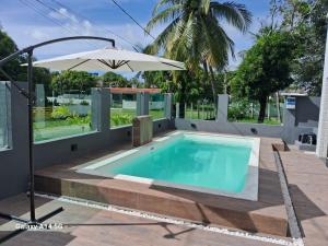 a swimming pool with an umbrella and an outdoor swimming pool at Pousada Pedra que Canta in Itamaracá