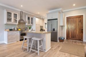 a kitchen with white cabinets and a island with stools at 11 Bonabali in Ballito +2 photos
