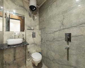 a bathroom with a white toilet and a sink at Hotel Sunshine Suites IGI Airport in New Delhi