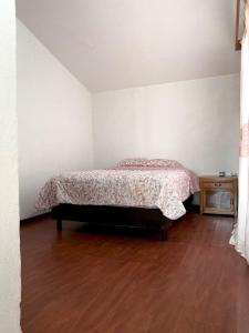 a bedroom with a bed and a wooden floor at Cozy house in the Angelópolis area in La Concepción