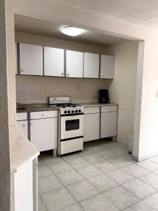 a kitchen with white cabinets and a stove in it at Cozy house in the Angelópolis area in La Concepción