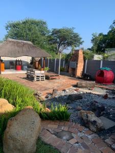 a patio with a table and a umbrella and rocks at Cottage @19th in Pretoria