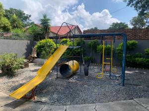 a playground with a yellow slide in a yard at Cottage @19th in Pretoria