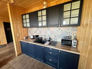 a kitchen with blue cabinets and a microwave at Domki Baby Jagi in Krajno Pierwsze +11 photos