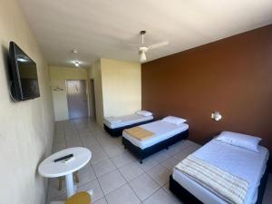 a hotel room with two beds and a tv at Hotel Guaporé - Campo Bom RS in Campo Bom