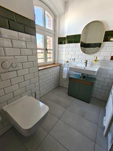 a bathroom with a toilet and a sink and a mirror at 3sine - Ihr besonderer Gasthof im Bahnhof Deisenhofen in Oberhaching