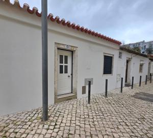 a white building with a door on a brick street at Casinhas da Ajuda nº15 in Lisbon