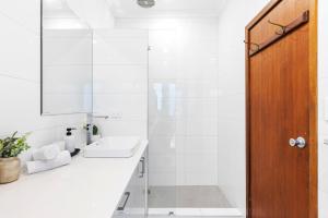 a white bathroom with a sink and a mirror at North Perth 3BR Home Steps To Hyde Park & Dining in Perth +21 photos
