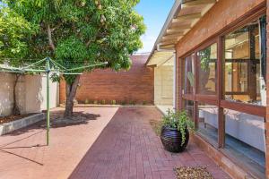 a brick walkway next to a building with a tree at North Perth 3BR Home Steps To Hyde Park & Dining in Perth