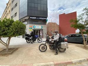 a man sitting on a motorcycle in front of a building at Wassime location in Taourirt