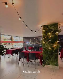 a restaurant with red tables and chairs and a christmas tree at Hotel Portal Central in Medellín