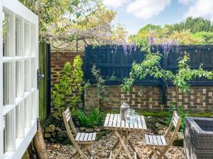 a garden with two chairs and a table and a fence at Old Rectory Cottage in Fernhurst