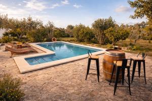 a pool with a barrel next to a table and chairs at Villa Es Puig, piscina y vistas a la montaña in Santa Margalida